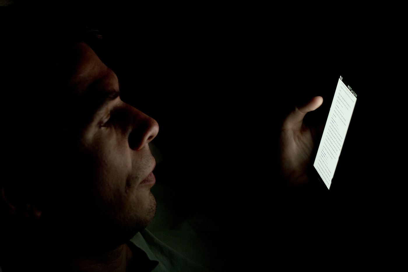 Gesicht im Licht eines Smartphone-Bildschirms bei Nacht