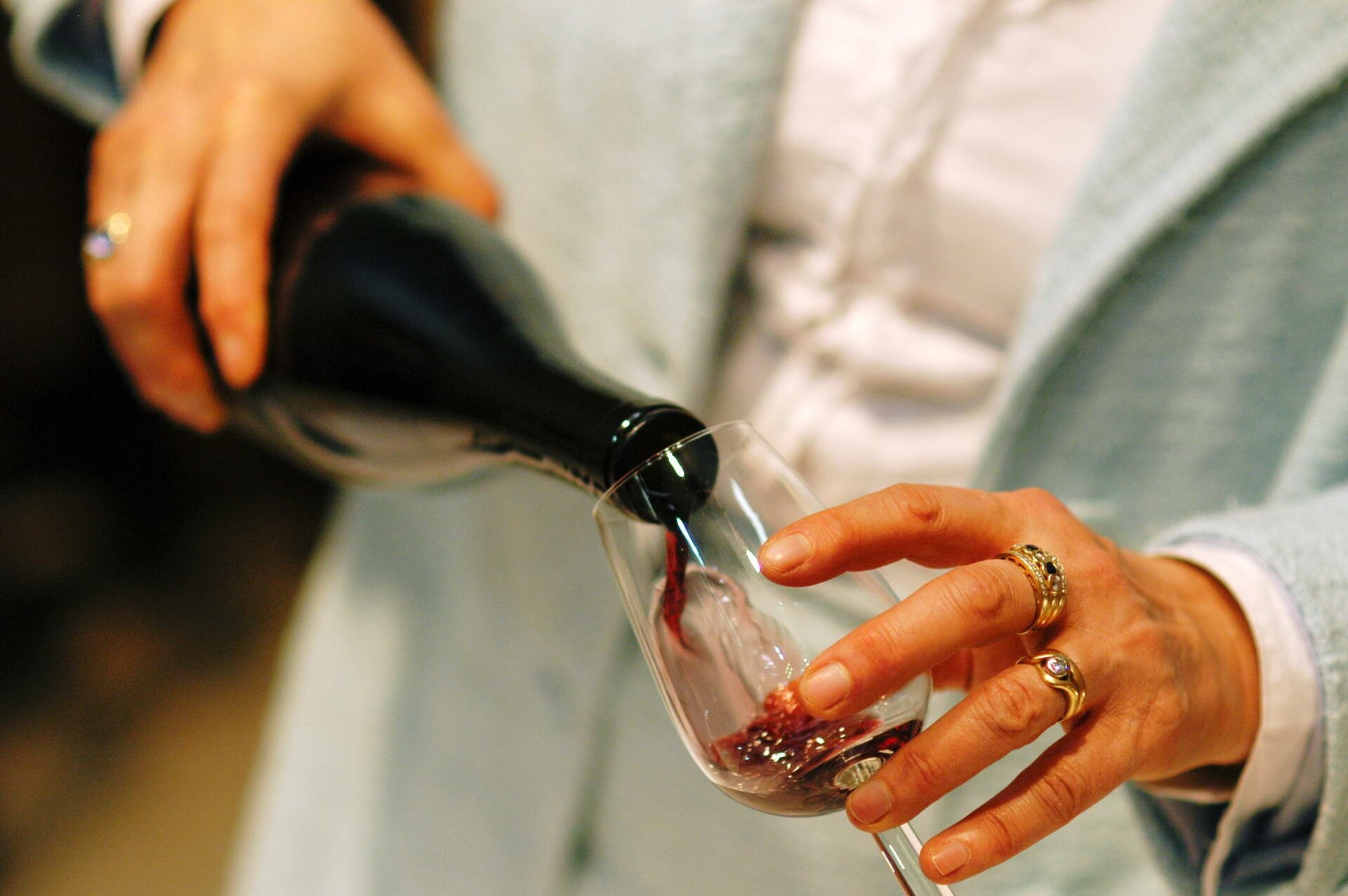 Rotwein wird aus der Flasche in ein Glas eingeschenkt