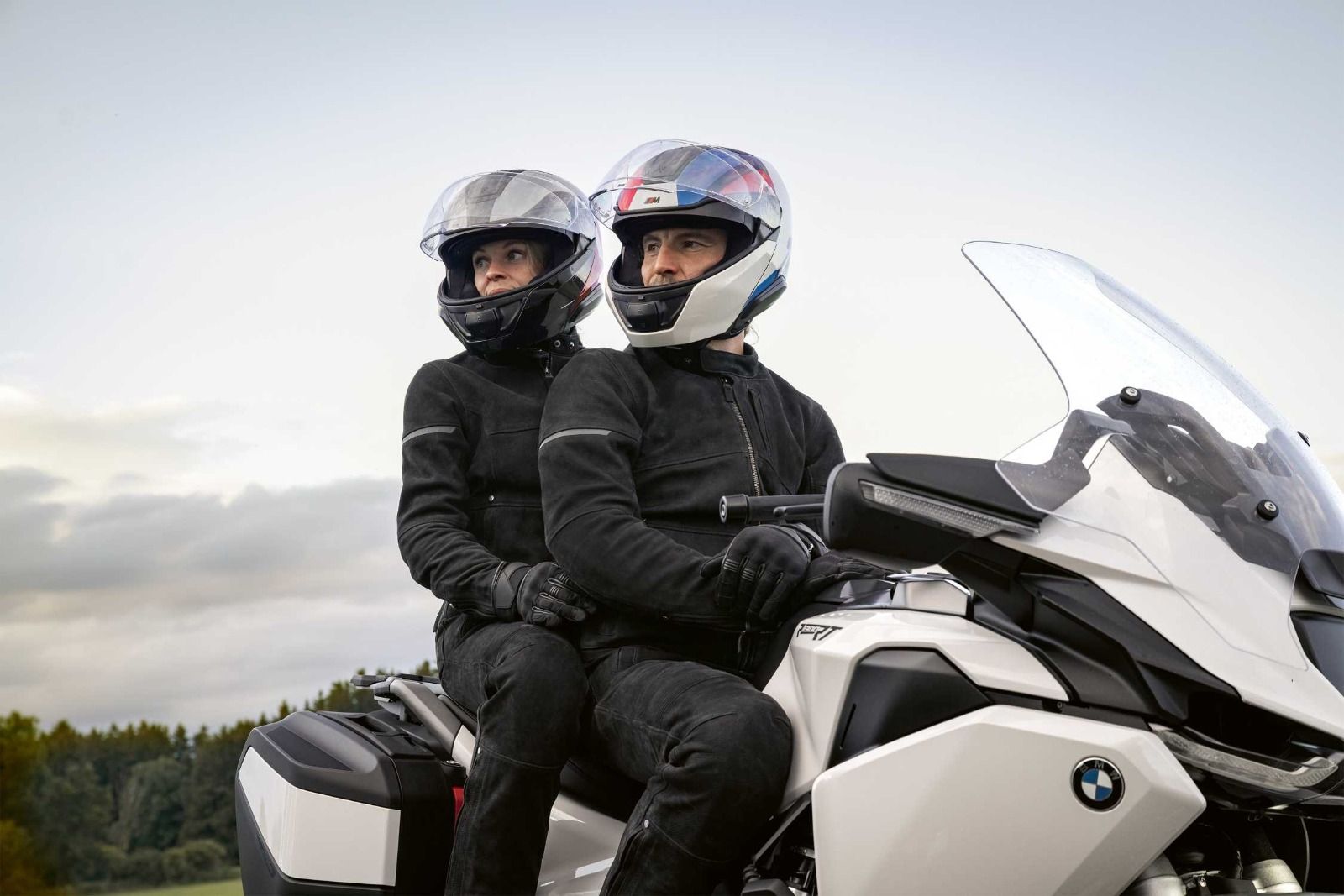 Ein Paar in Motorradkluft sitzt auf einem weißen BMW-Tourer